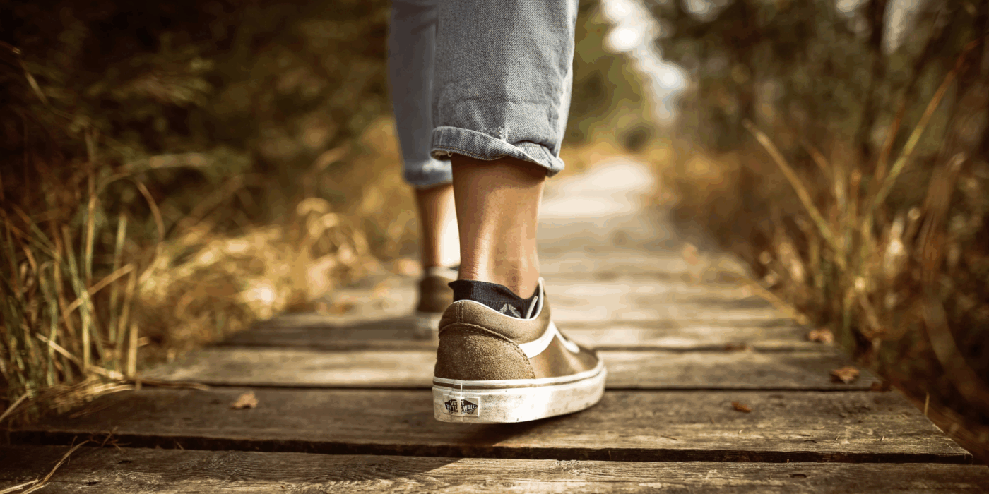 Person walking on a deck through the woods.