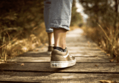 Person walking on a deck through the woods.