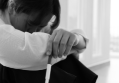 Image of woman with her arms wrapped around her legs and head in her knees.