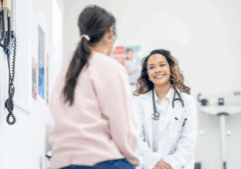 Two females, one a patient and one a doctor sat talking in a health office.