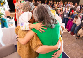 Women hugging on stage at One Woman Conference