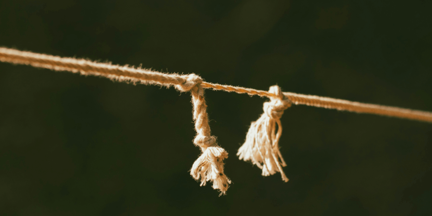 Rope pulled taut which is fraying and holding on by one thread.