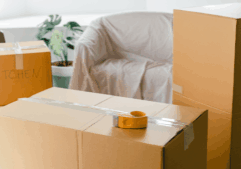 A close up shot of moving boxes with sofa and plant in background and texrt overlay 'Holding it all together, during big life shifts'.