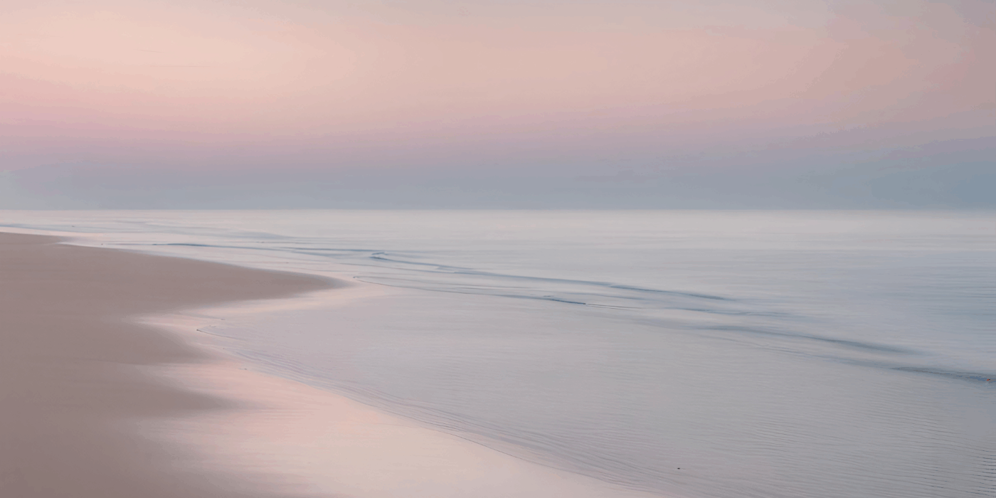 Low tide lapping on the beach during a soft sunrise.