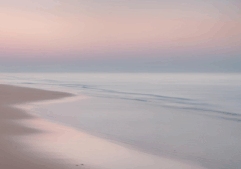 Low tide lapping on the beach during a soft sunrise.